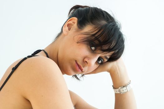Pretty brunette girl looking serious at camera resting head on hand, on white background, close up