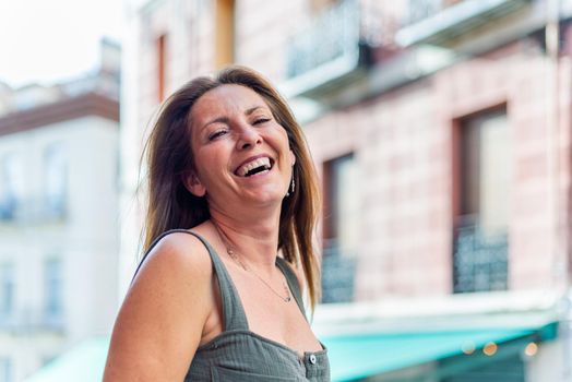Portrait of a beautiful matuire adult woman laughing at camera. Adult woman standing and looking at camera outside.