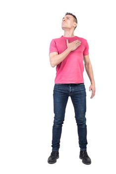 Full body of honorable male patriot looking up with hand on chest while standing isolated on white background in light studio