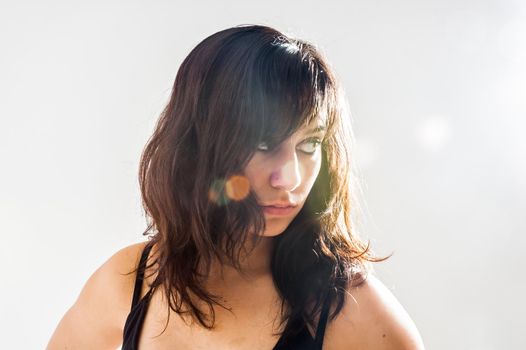 Thoughtful pretty brunette girl with long hair, looking sideways, on white background , close up