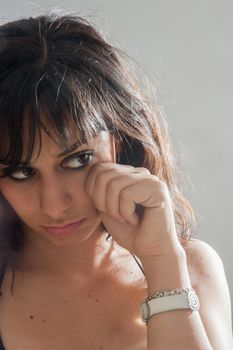 Sad pretty brunette girl with long hair, looking sideways on white background, close up