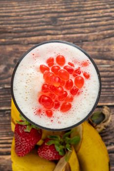 Banana, strawberry and pineapple smoothie on wooden table and bubble tea or boba tea balls on it