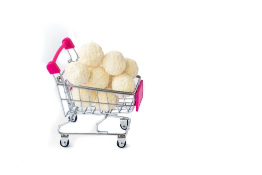 coconut round candies in a mini shopping basket, isolate on a white background. Supermarket shopping concept. full cart of sweets. High quality photo