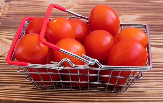 small cherry tomatoes in a grocery basket. On a wooden burnt background. The concept of buying vegetables from a farmer online. High quality photo