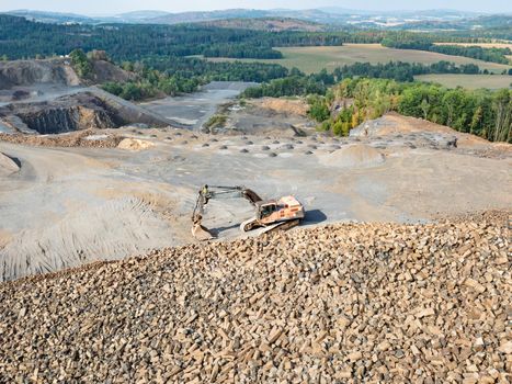 Loader wait for dump truck. Heavy machinery in the clinkstone or phonolite mining quarry. The excavators  crusher with belt conveyor puts crushing and screening process