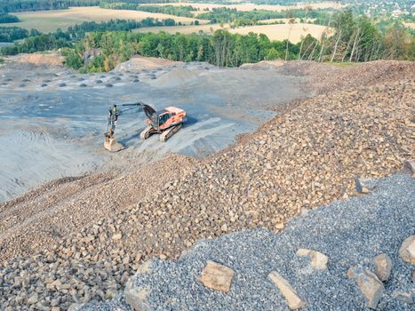 Loader wait for dump truck. Heavy machinery in the clinkstone or phonolite mining quarry. The excavators  crusher with belt conveyor puts crushing and screening process