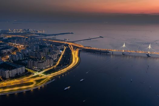 A picturesque sunset over the cable-stayed bridge and Vasilevsky island, passenger sea port, illuminated highway. High quality photo
