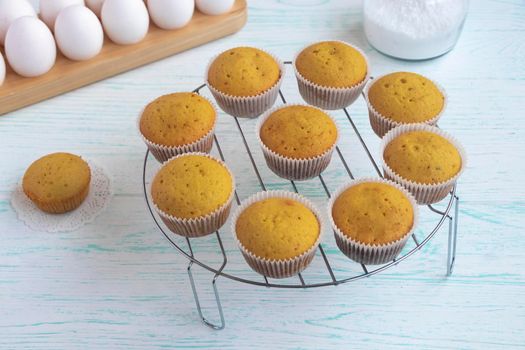 muffins are cooled on a pastry steel grate. Home baking concept. cupcakes on a light table on a background of eggs. High quality photo