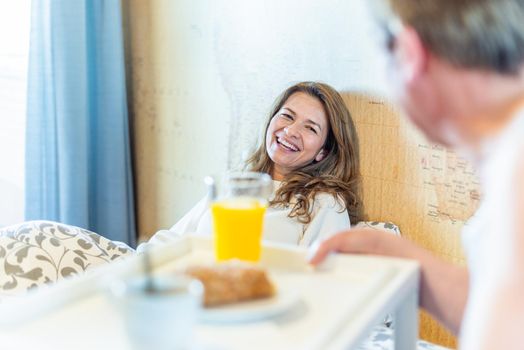 Mature man in love bringing his wife breakfast in bed on a tray. High quality photo