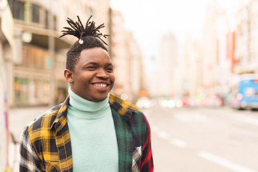 Young black man in the middle of the city, smiling. Selective focus.