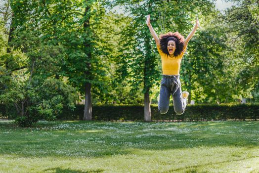 Pretty woman jumping happily in a garden. Front plane. Full body.