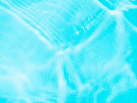 Ripple water texture on blue pool background. Shadow of water on sunlight. Mockup for product, spa or travel background. Marble blue water surface as wallpaper background