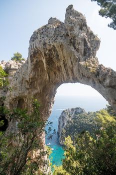 View of natural rock arch with the sea in the background. Vertical framing. Capri island, Italy.