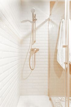 Vertical image of shower zone in a white, beige hotel bathroom. Concept of vacation, hotel.