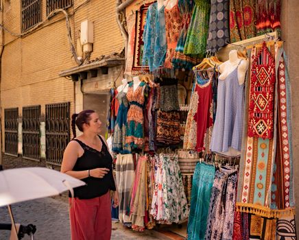 Lifestyle shopping concept, young happy caucasian woman choosing clothes in store on shopping street at daytime. stock photography