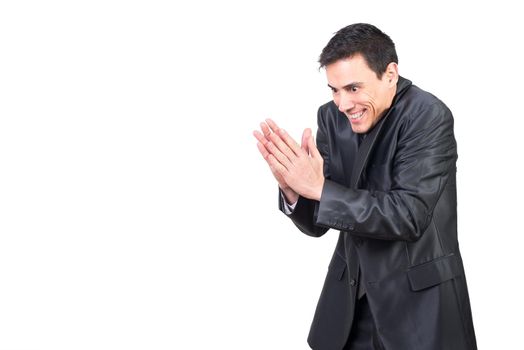 Vicious male with black hair in formal suit rubbing hands with evil face while standing isolated on white background in light studio