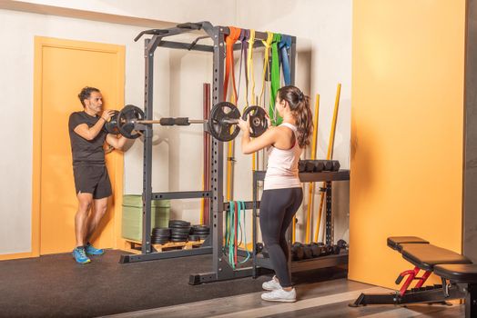 Sporty man and woman putting weight plate on bar in gym. Concept of equipment in gym.