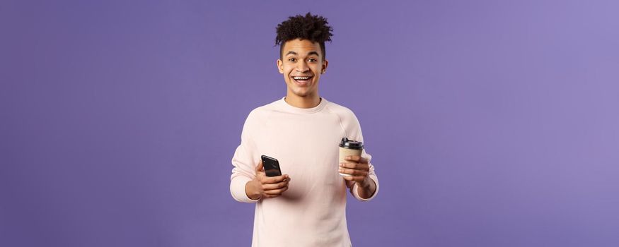 Waist-up portrait of happy enthusiastic hispanic man with smartphone, hold mobile phone and drinking coffee from take-away cup in office cafe, discuss recent project coworkers and team.