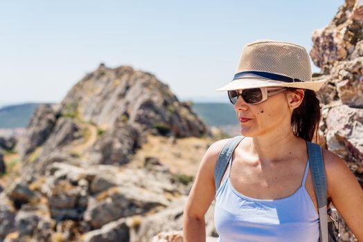 Profile portrait of a woman wearing a hat and sunglasses on a rocky hilltop in Toledo, Spain