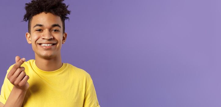 Lovely young romantic boyfriend, guy showing korean heart with fingers and smiling, like someone, being in love, show sympathy, standing purple background grinning upbeat.