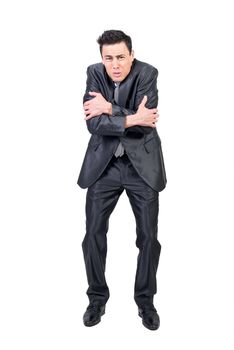 Full body of male in suit embracing himself and feeling cold on white background in studio while looking at camera