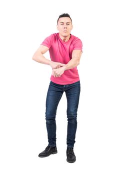 Full body of male model in casual wear pointing on wrist and accusing of being late on white background and looking at camera