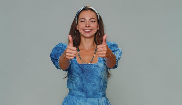 Like. Lovely pretty young woman raises thumbs up agrees with something or gives positive reply recommends advertisement likes good. Adult stylish girl isolated alone on gray studio background indoors