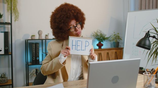 Hopeless sad businesswoman in formal wear suit working on laptop computer, showing inscription note text Help. Overworked tired freelance business woman indoors at office. Poverty, bankrupt, deadline