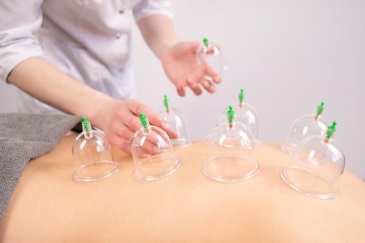 Female massage therapist uses vacuum cans on the patient's back