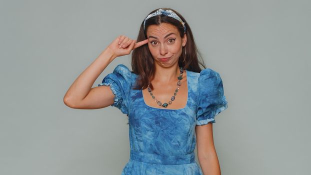 You are crazy, out of mind. Lovely pretty young woman pointing at camera and showing stupid gesture, blaming some idiot for insane plan. Adult stylish girl isolated on gray studio background indoors