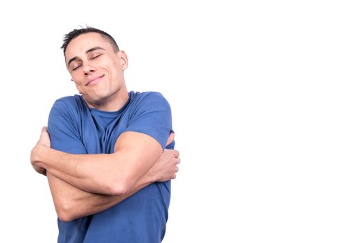 Studio photo with white background of a happy man hugging himself as he closes his eyes