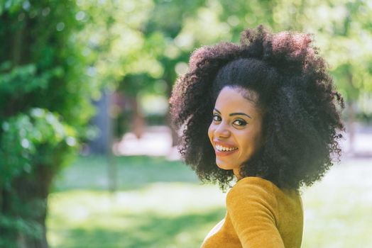 Portrait of nice and happy afro girl in a garden. Close up. Selective focus