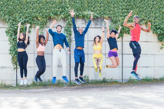 Group of runners jumping at the same time in a park. Horizontal framing.