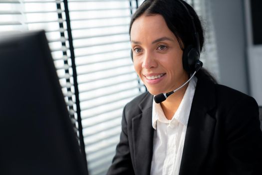 Competent female operator working on computer and talking with clients. Concept relevant to both call centers and customer service offices.