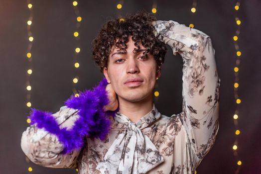 Portrait of a young gay man looking at camera with a blurred light background in a nightclub