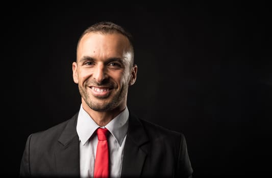 Handsome and smiling man in suit. Close up. Black background.