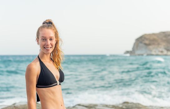 young redhead girl in bikini posing in front of the sea, horizontal portrait