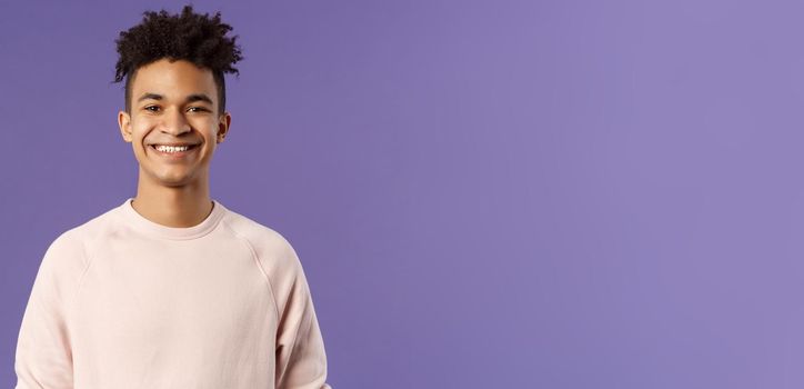 Close-up portrait of cheerful young hipster guy with dreads, smiling optimistic and delighted, standing purple background, having lucky good day, express positivity and joy.