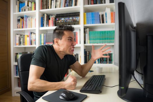 Seated man in a black shirt in front of the computer, hysterical because he does not understand something. Mid shot.