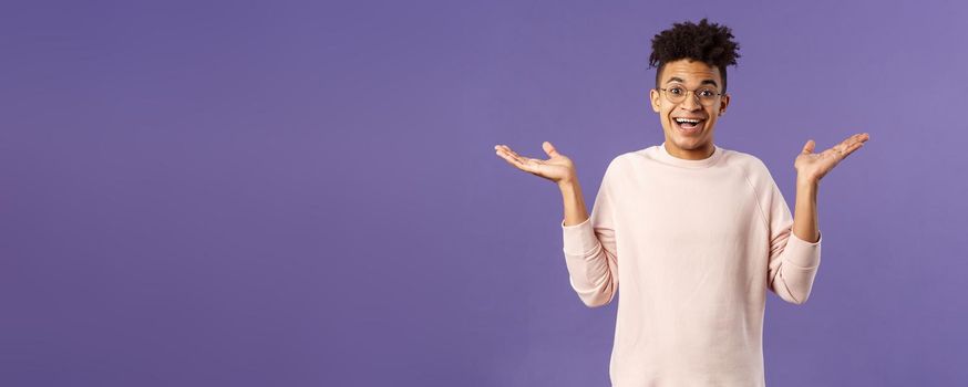 So what, I wear glasses. Portrait of unbothered, happy optimistic guy with dreads, wear round eyewear, shrugging carefree and raise hands sideways, smiling cheerful, have no worries.