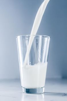 Dairy, healthy nutrition and breakfast concept - World Milk Day, pouring into glass on marble table