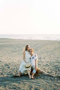 Young woman sitting on man lap on the beach. High quality photo