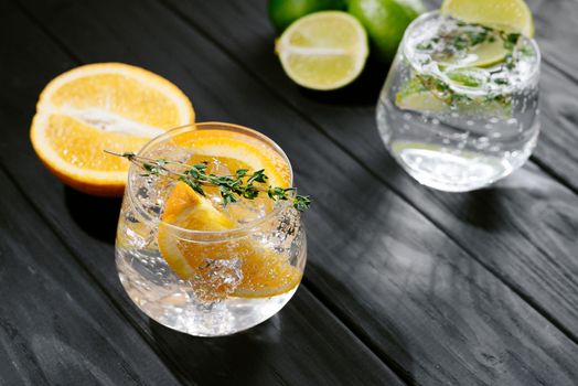 two glasses with an alcoholic cocktail on a wooden dark background. hard seltzer is a low-alcoholic drink. Strong seltzer cocktails with lime. Alcoholic cocktail tonic clear. hard seltzer is a low-alcohol drink consisting of alcohol, carbonated water and fruit, berry and herbal flavorings