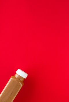 Detox, diet and healthy lifestyle concept - Chocolate banana smoothie bottle on red, flatlay