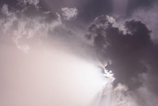 From below black and white of cloudy vast sky with radiant sun behind clouds during daytime