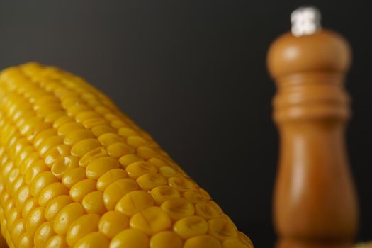 close-up macro shot of a fresh ear of corn with an out-of-focus pepper pot in the background
