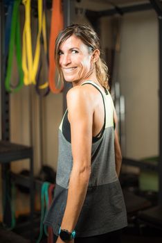 Rear side view of cheerful athlete woman in gym looking at camera. Concept of people in gym.