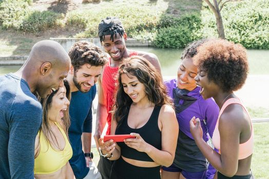 Group of runners looking at something very funny on a mobile. Horizontal framing.