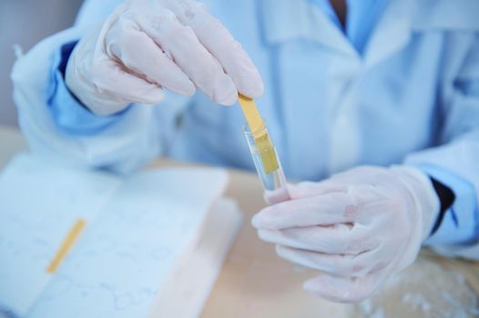 Close-up. Selective focus on the hands of scientist, laboratory assistant measuring PH , alkalinity acidity of chemical substance, dipping a strip of litmus paper into a liquid solution in a test tube