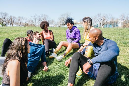 Group of runners in a park lying on the grass. Talking and laughing. Horizontal framing.